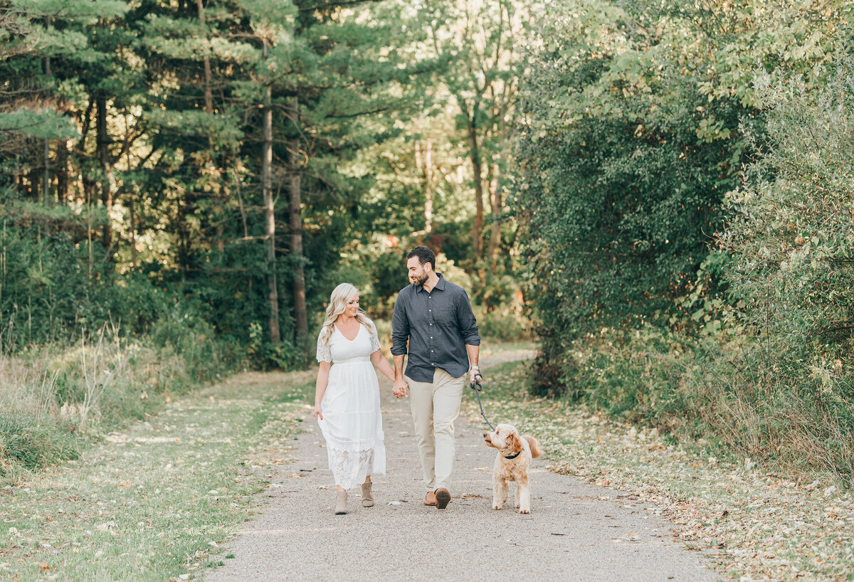 Couple posing with their dog for their forest engagement session in London Ontario
