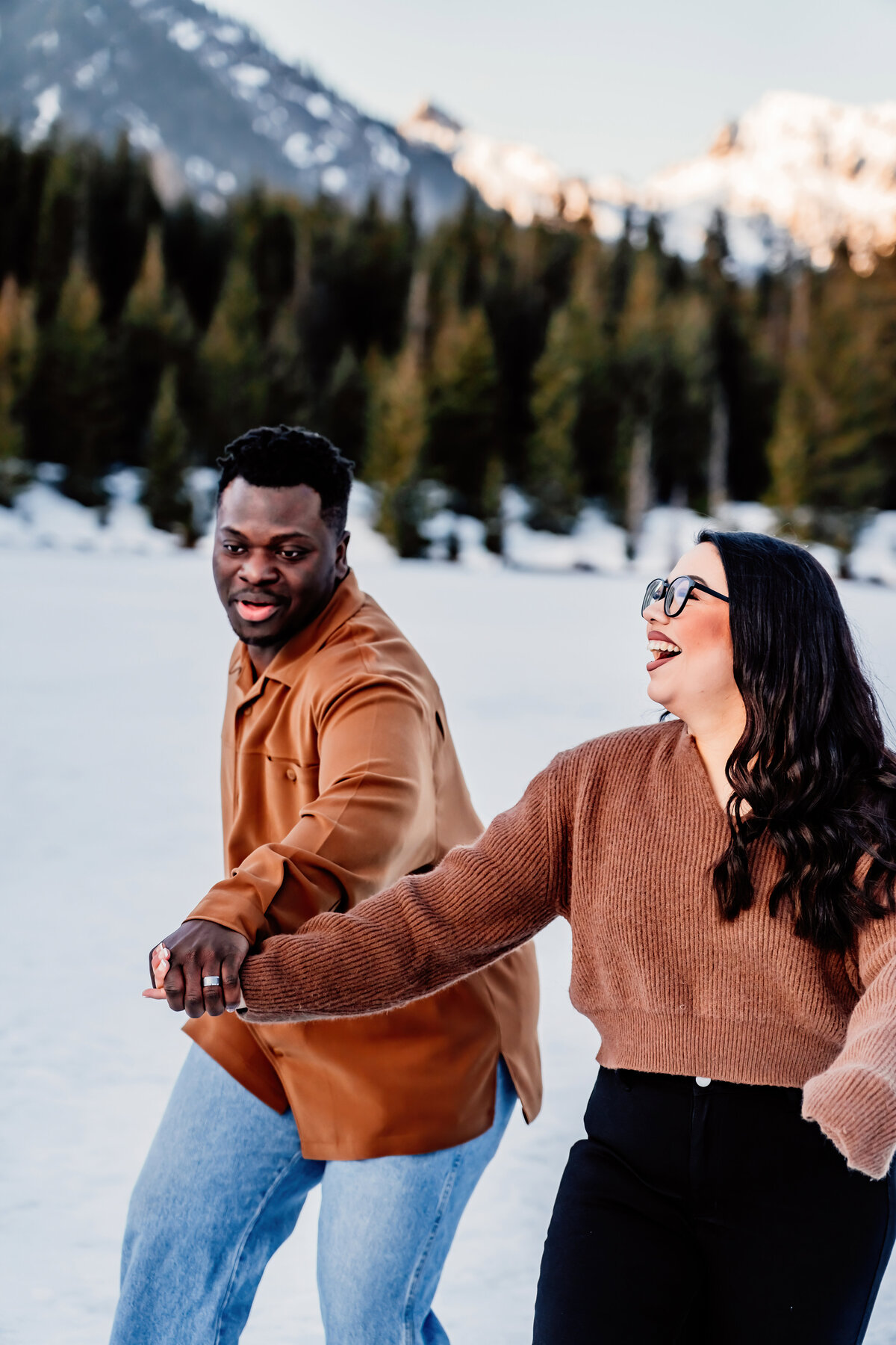 a husband and wife holding hands, having fun in the snow at Gold Creek Pond, WA