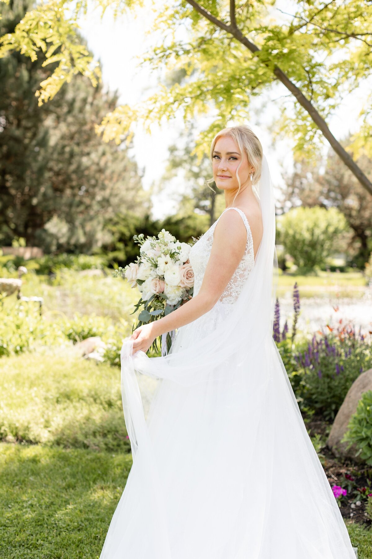 Bride-swishing-veil-ovelooking-the-pond-at-hessenland-vineyard-in-ontario