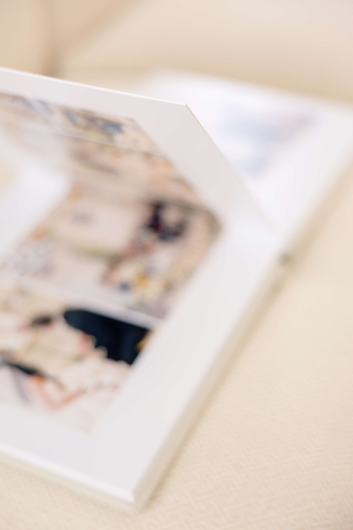 An open photo album with blurred images on its pages, placed on a light-colored surface.