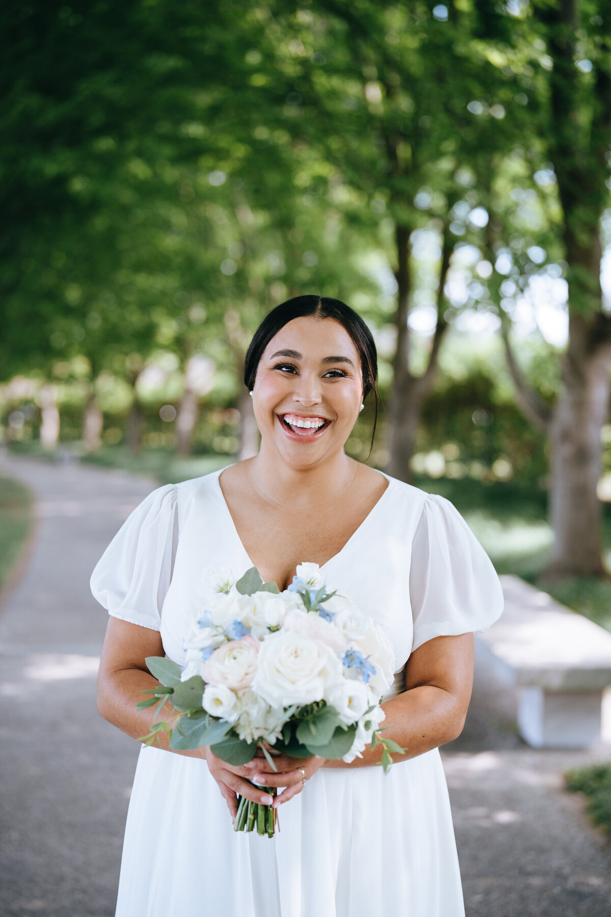 bride smiling while holding wedding bouquet at forest park