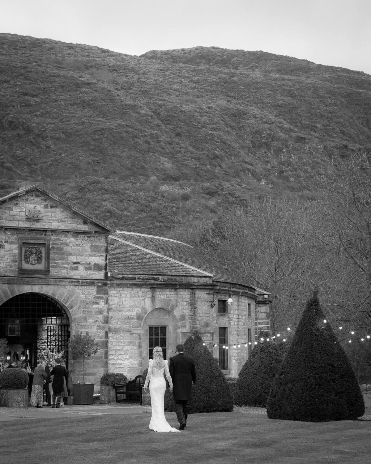 Couple walk in front of Arthurs seat in the distance