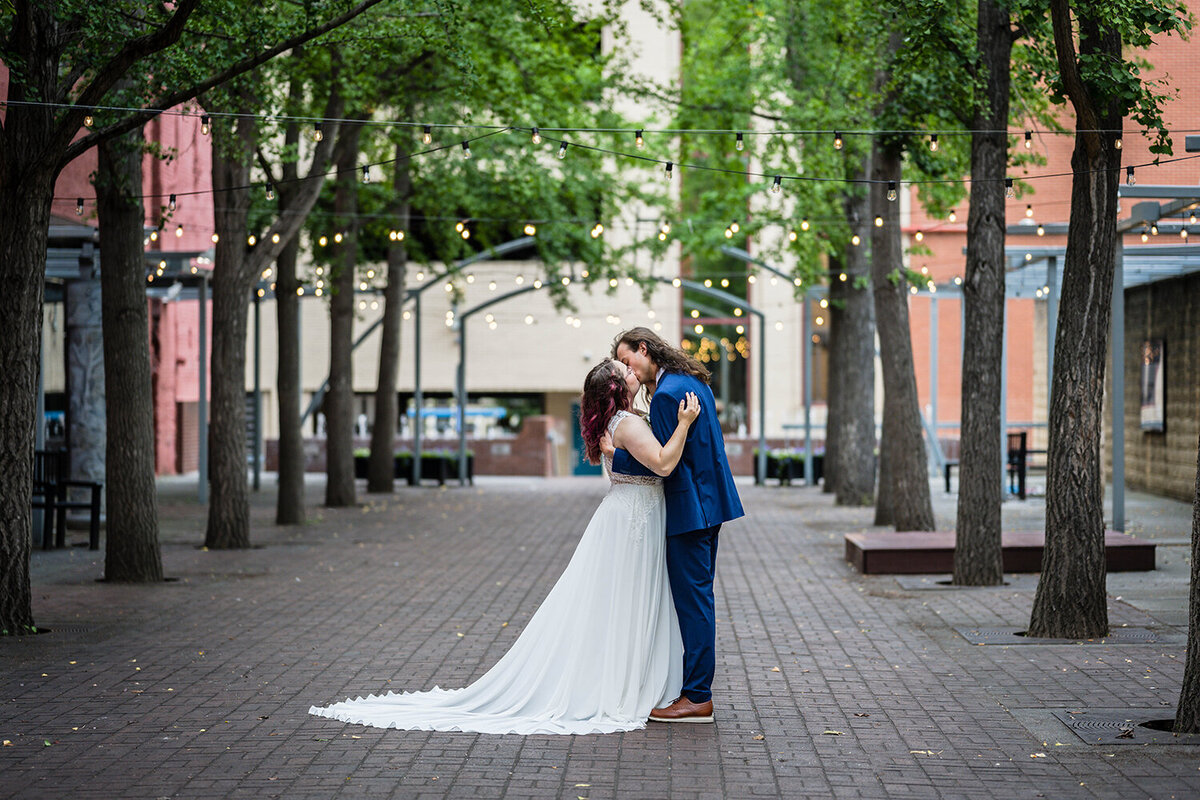 Two newlywed marriers go in for their first kiss on their elopement day in a secluded, private, tea-lit alley in Roanoke, Virginia.