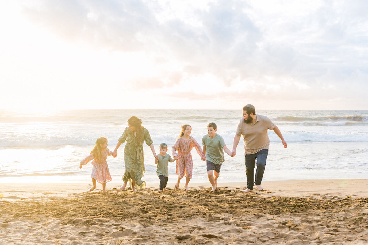 Photo of family running in the sand in Hawaii during a photo session