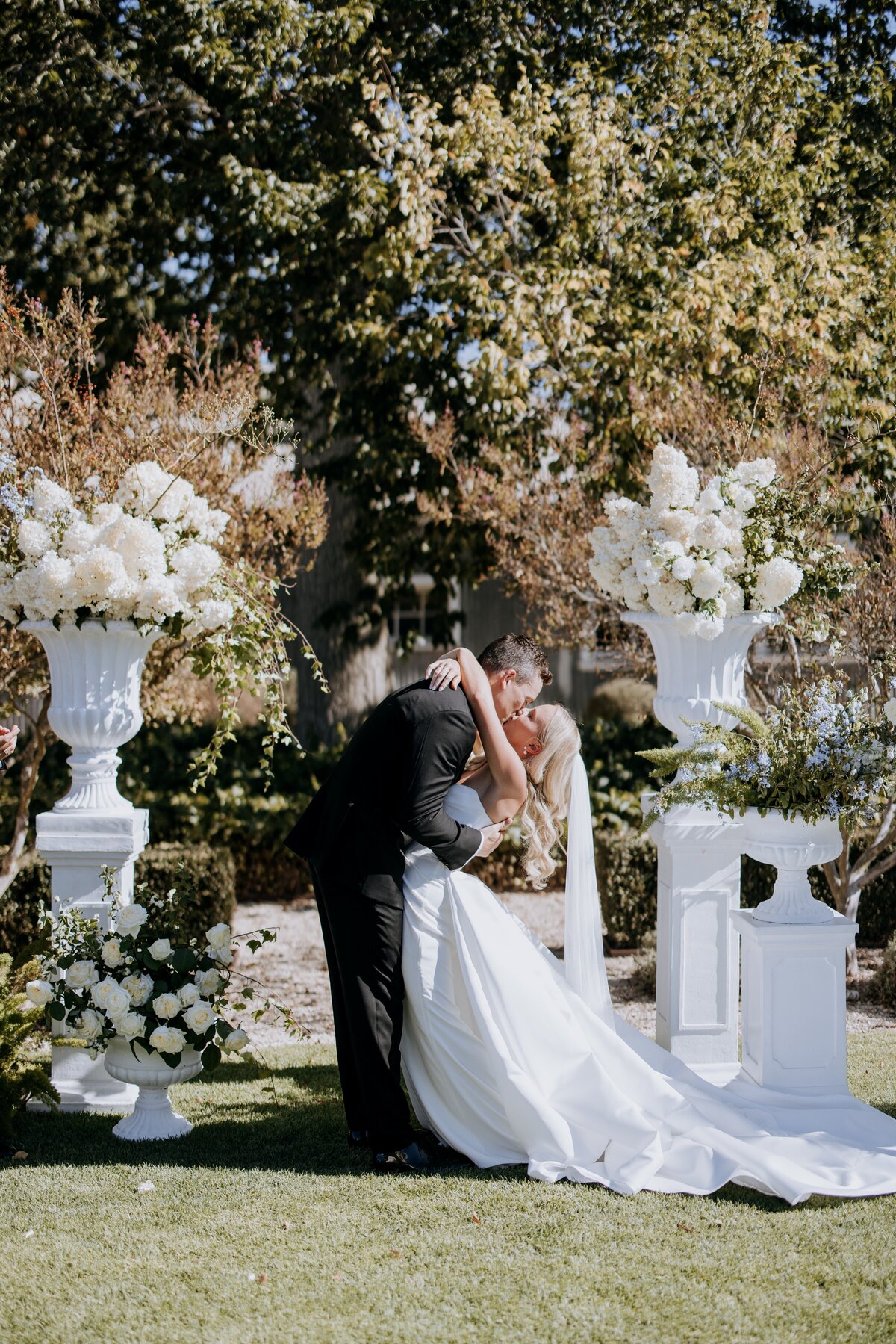 Bride and Groom kissing in front of flower arrangement