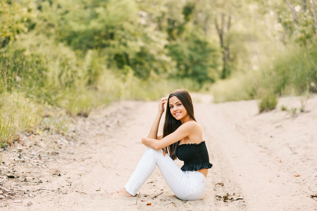Photo of a high school senior girl sitting in the sand at a beach in Erie Pa
