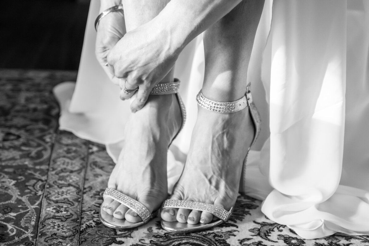 Bride buckling on her wedding shoes