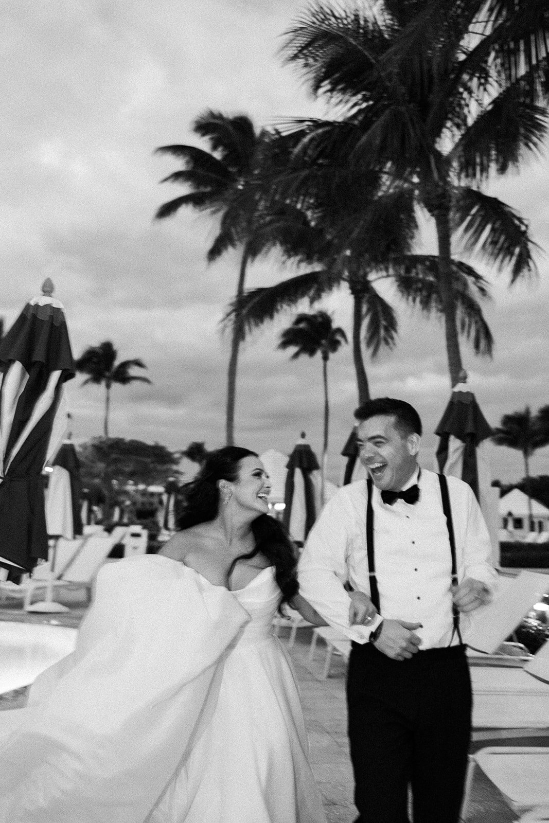 A candid moment of laughter shared between the bride and groom, surrounded by tropical palm trees at Ocean Reef in Key Largo.