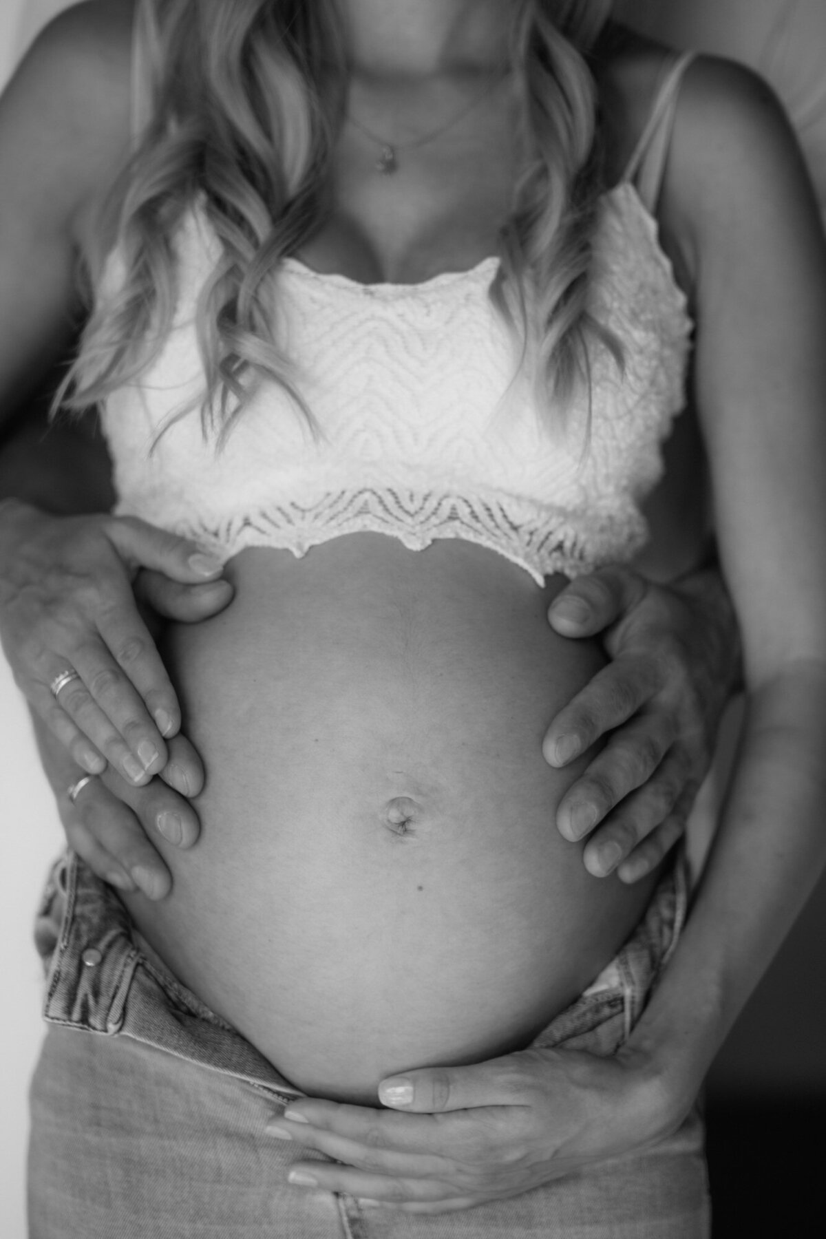 Closeup of a baby bump, being hold by the expecting couple.
