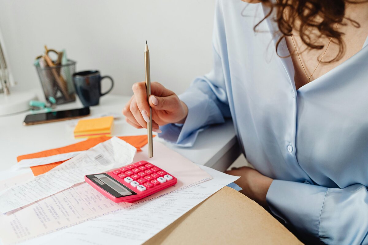 Hands signing formal documents with a gold pen on a white table, representing payroll processing or employee onboarding paperwork