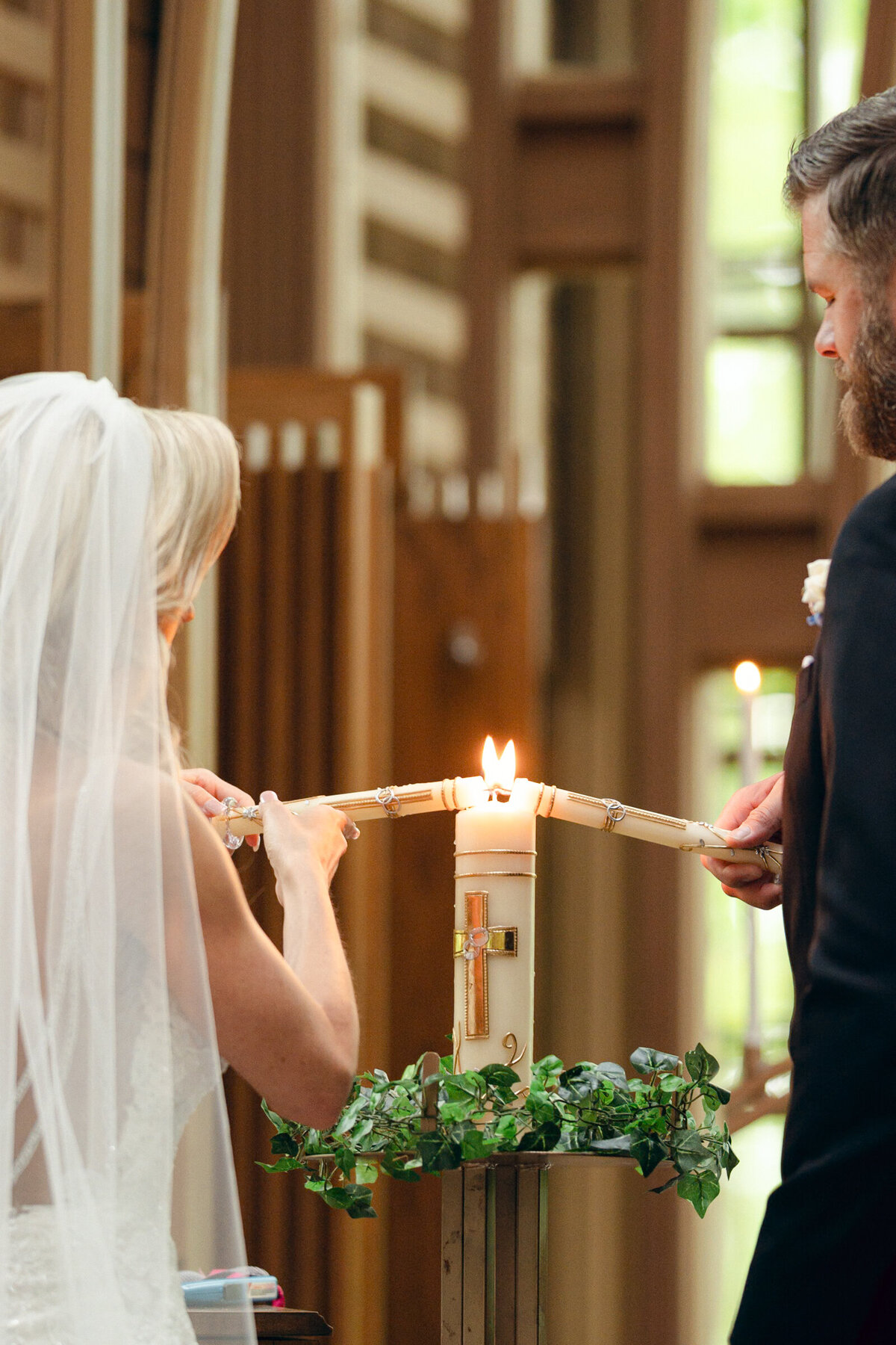 A wedding photo of the bride and groom lighting a candle during their wedding ceremony at Mildred B Cooper Chapel in Betonville Arkansas