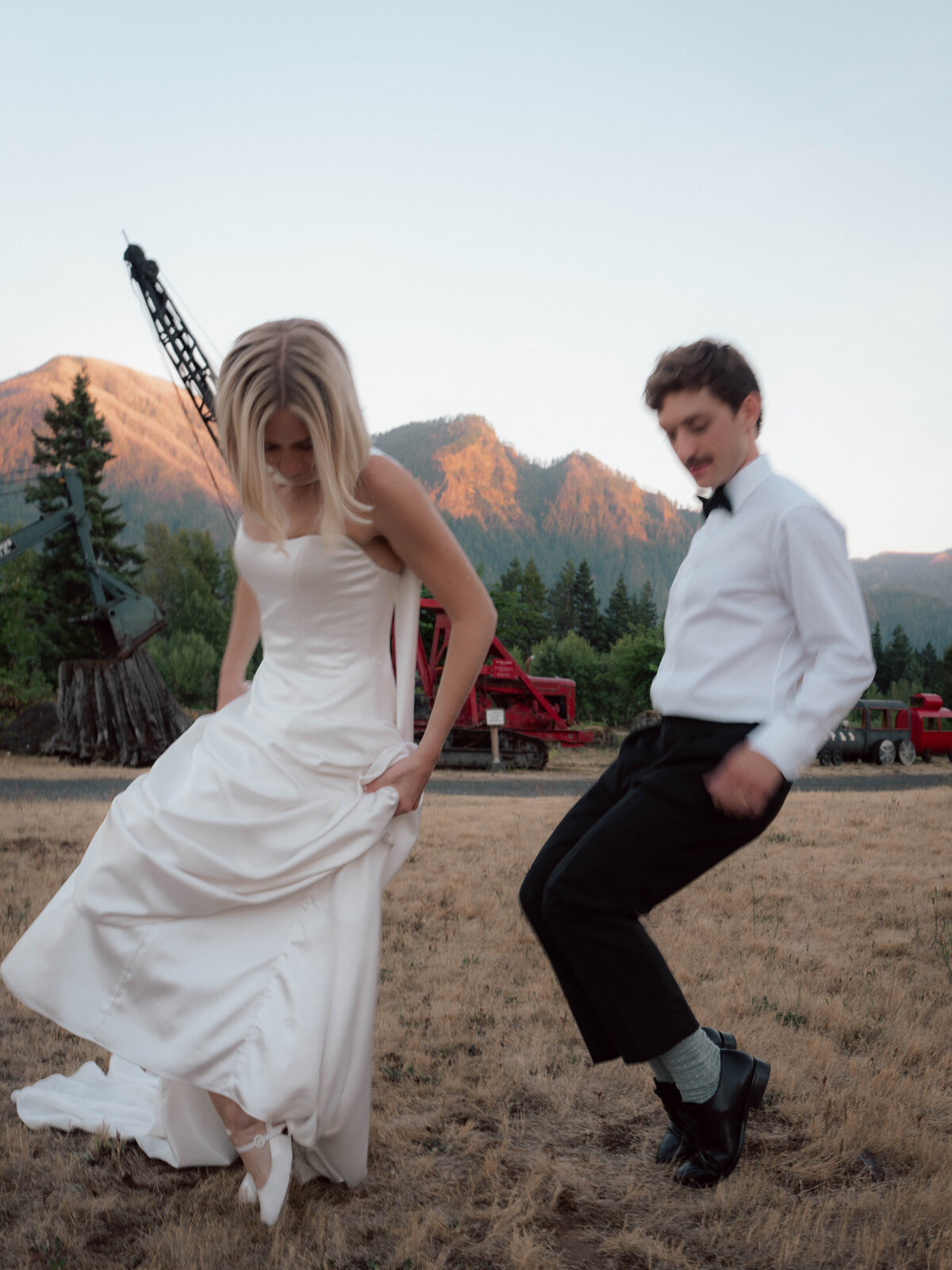 Bride and groom dancing playfully outdoors with Cascade Mountains in background