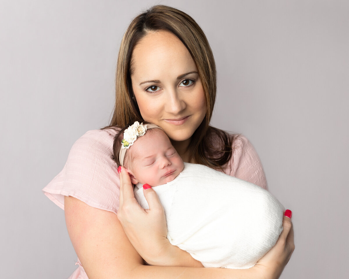 mom and newborn baby girl posing for studio portraits