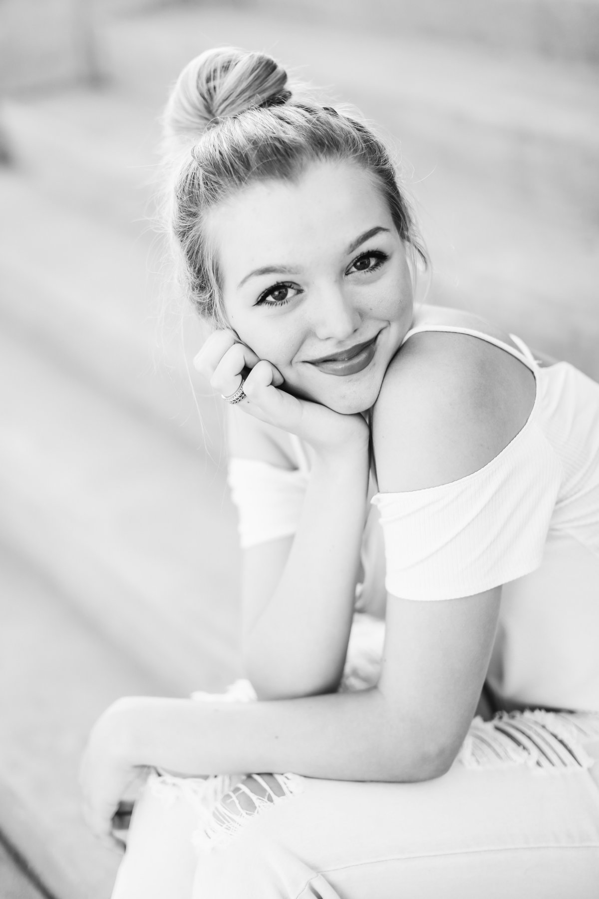 Black and white portrait of a girl sitting on steps smiling
