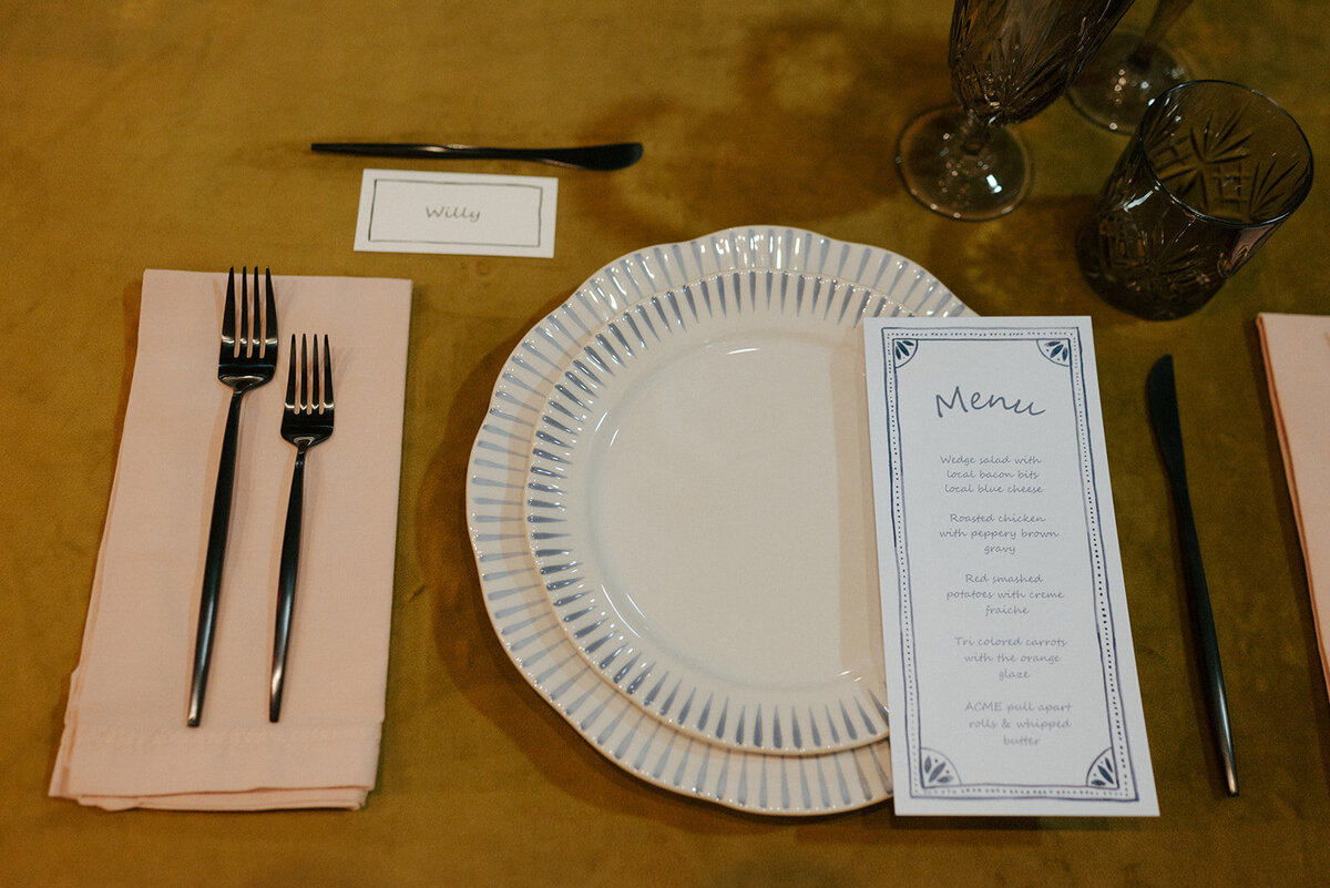 A table setting with a menu for an indoor vow renewal celebration