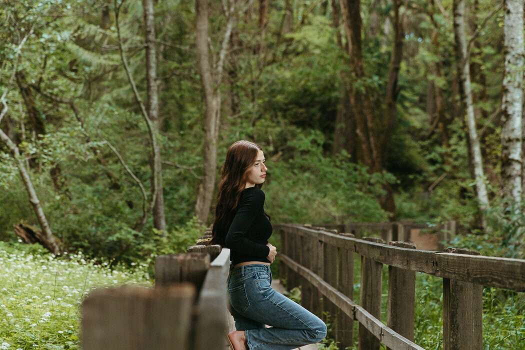 Senior girl standing on a bridge in the woods in Olympia WA
