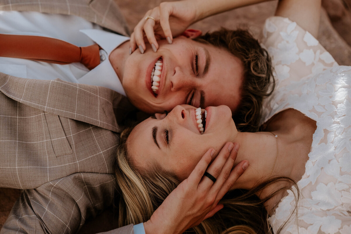 Bride and Groom laying with their heads together and showing off their new wedding rings