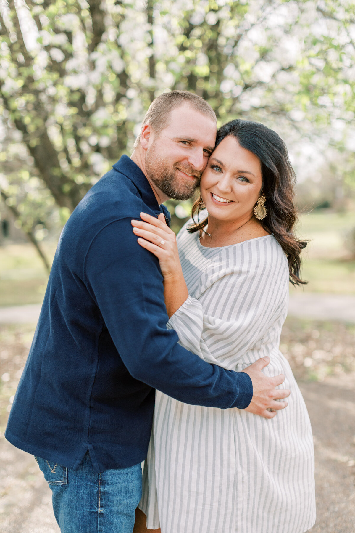 A couple stands with their cheeks smushed together.