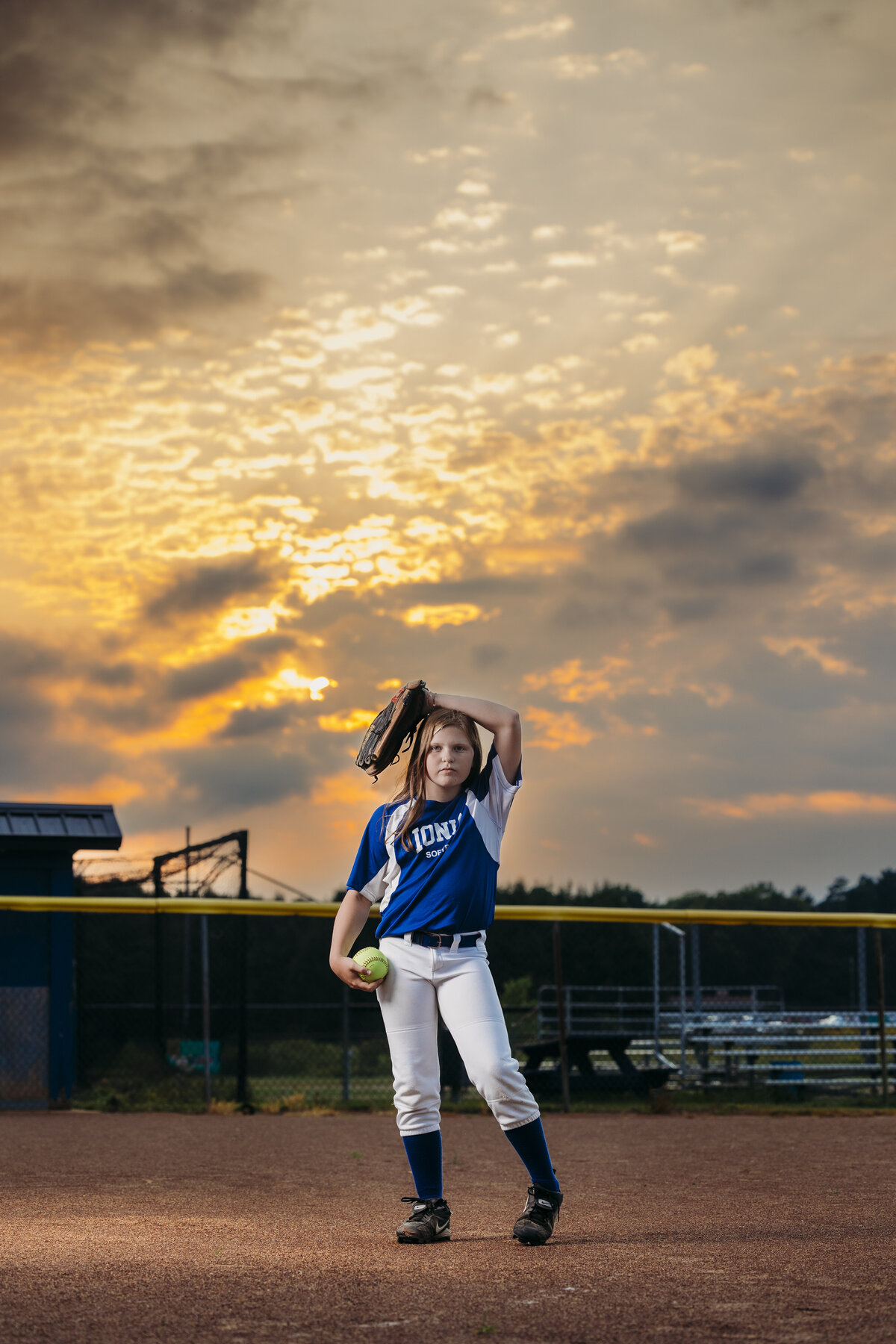 Young girl in softball gear posing on Ionia High School fields. 
