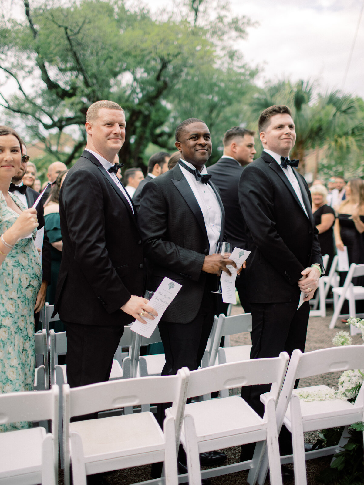 A trio of well-dressed men in tuxedos standing confidently for a portrait, representing sophistication and elegance at an upscale wedding ceremony, exuding charm and style.