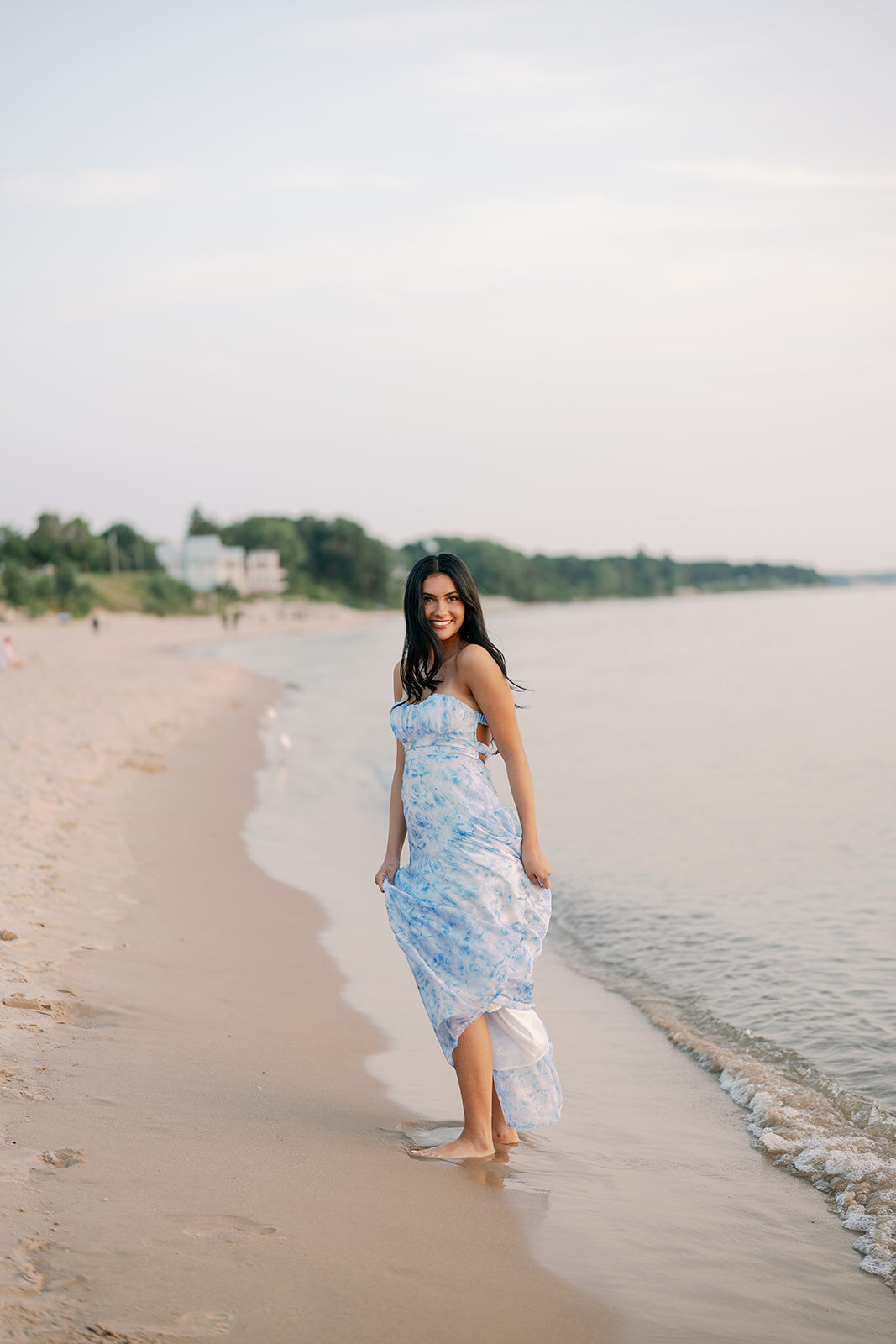 High school senior walking on the beach near lakeside homes during her South Haven North Beach senior session.