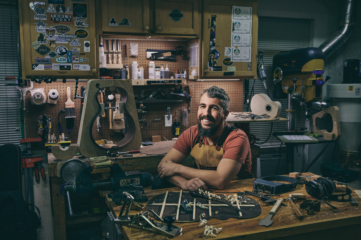 A man sitting at a bench in a workshop smiling