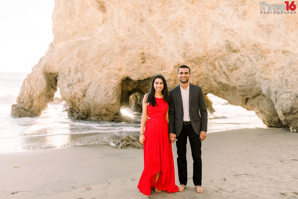 Newly engaged couple pose for the wedding photographer on the sandy beach