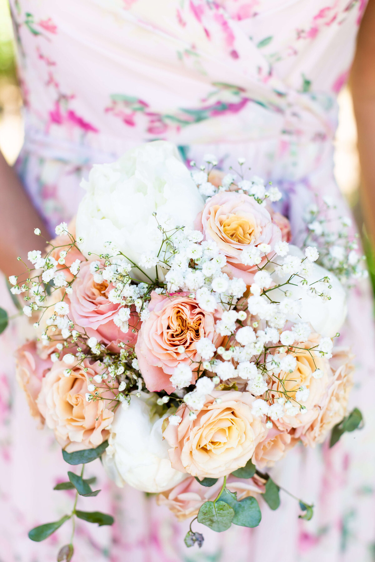 Bride holding a colorful bouquet of florals with peach, pinks and creams