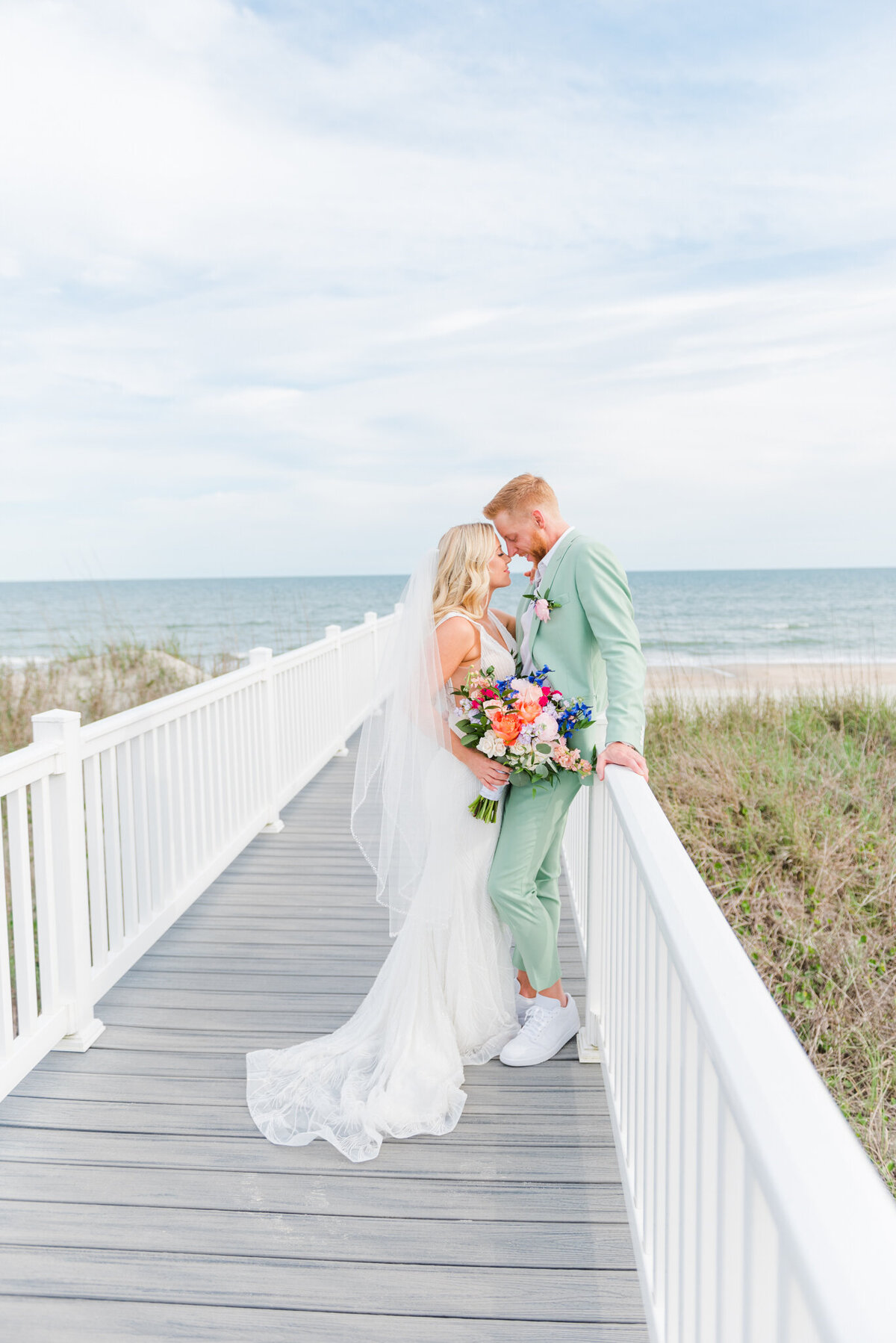 bride and groom kissing on dock at wrigthsville beach, nc
