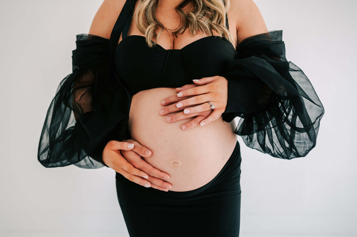 close up of pregnant baby bump with husband and wife hands during Joplin MO Maternity photography session