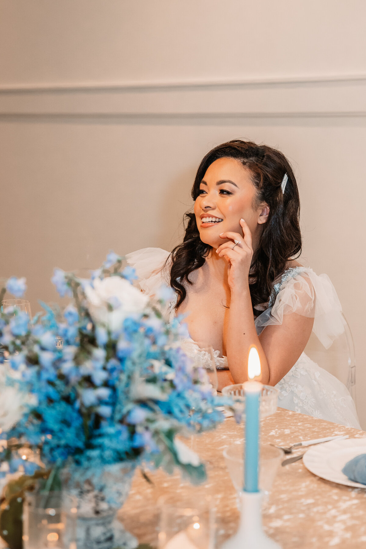 bride smiles at the head tables with flowers of blue