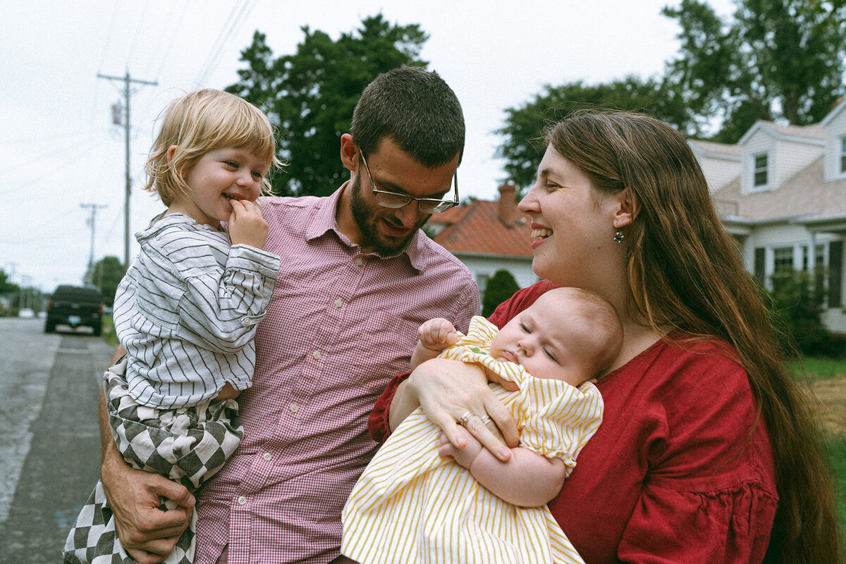 couple smiling holding two kids during family photos captured by NYC family photographer Elsie Goodman