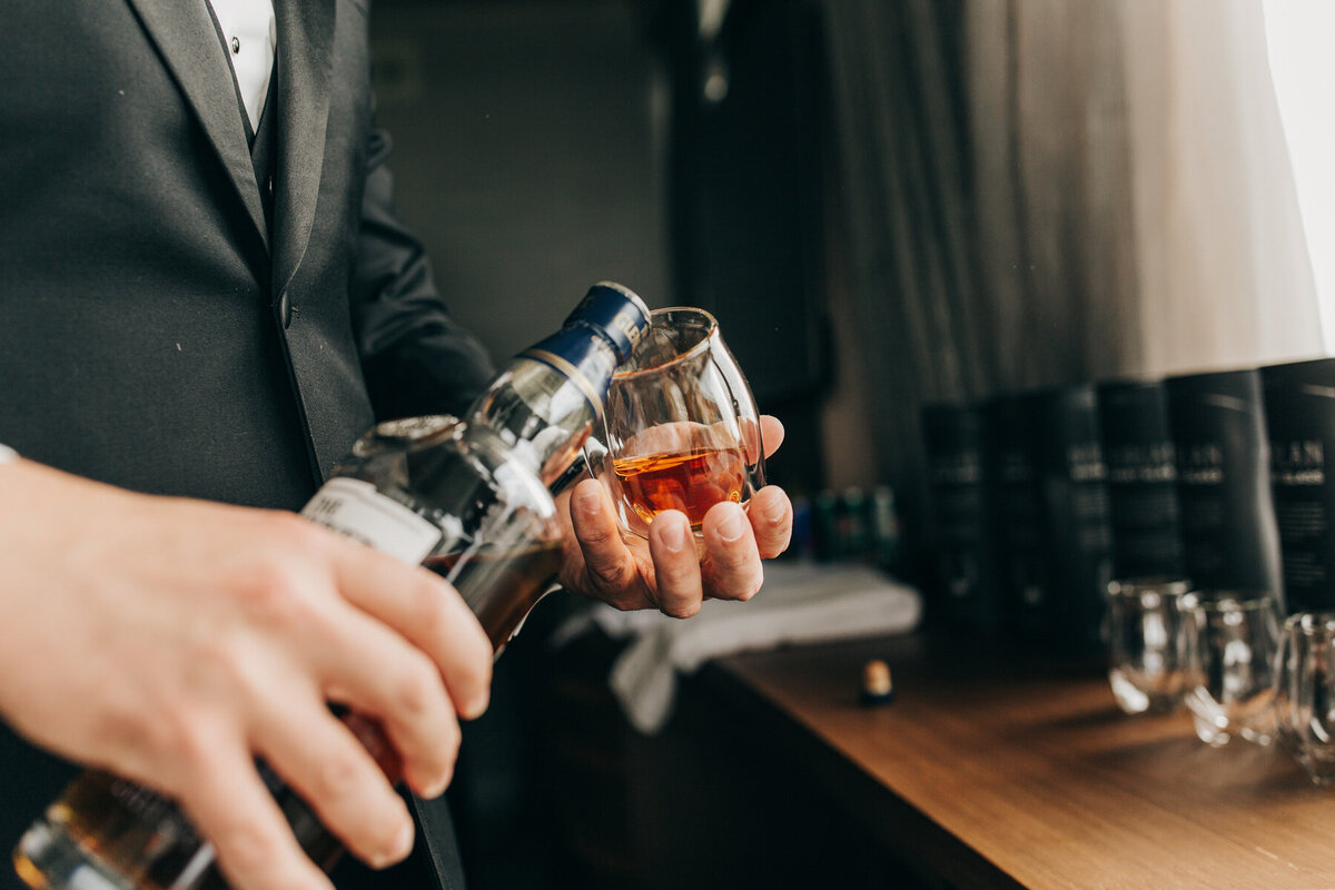 Groom pouring whisky white getting ready for luxurious wedding