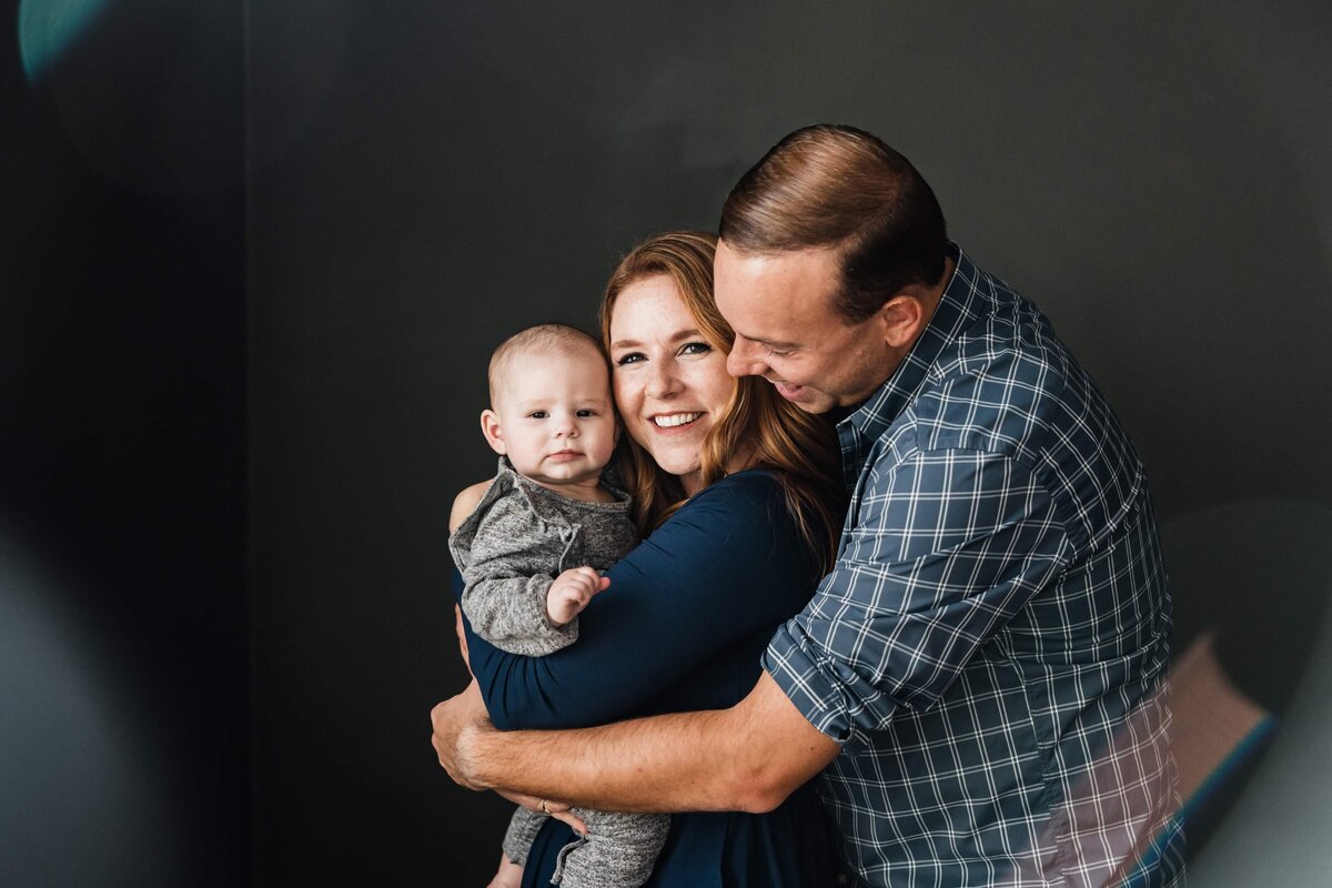 A family of three enjoying a tender embrace, captured by a skilled Pittsburgh family photographer.