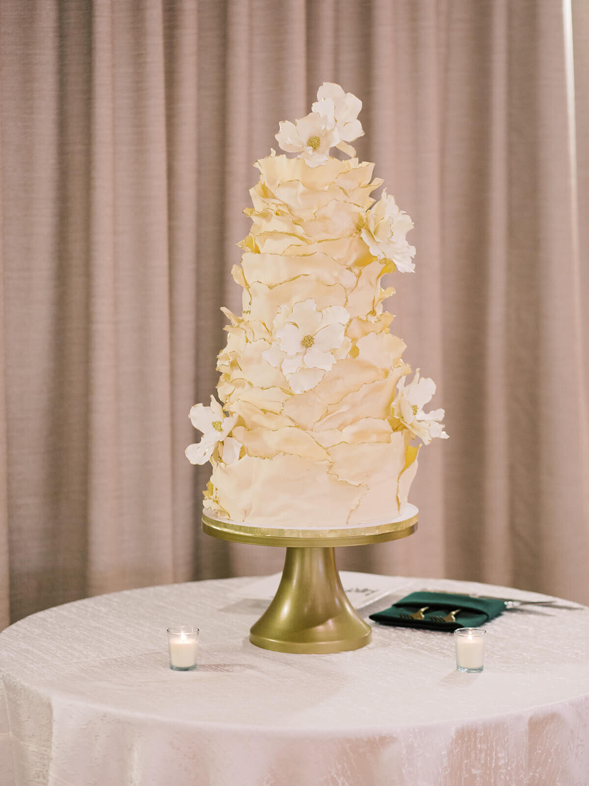 Custom fairytale wedding cake with floral accents on a gold stand