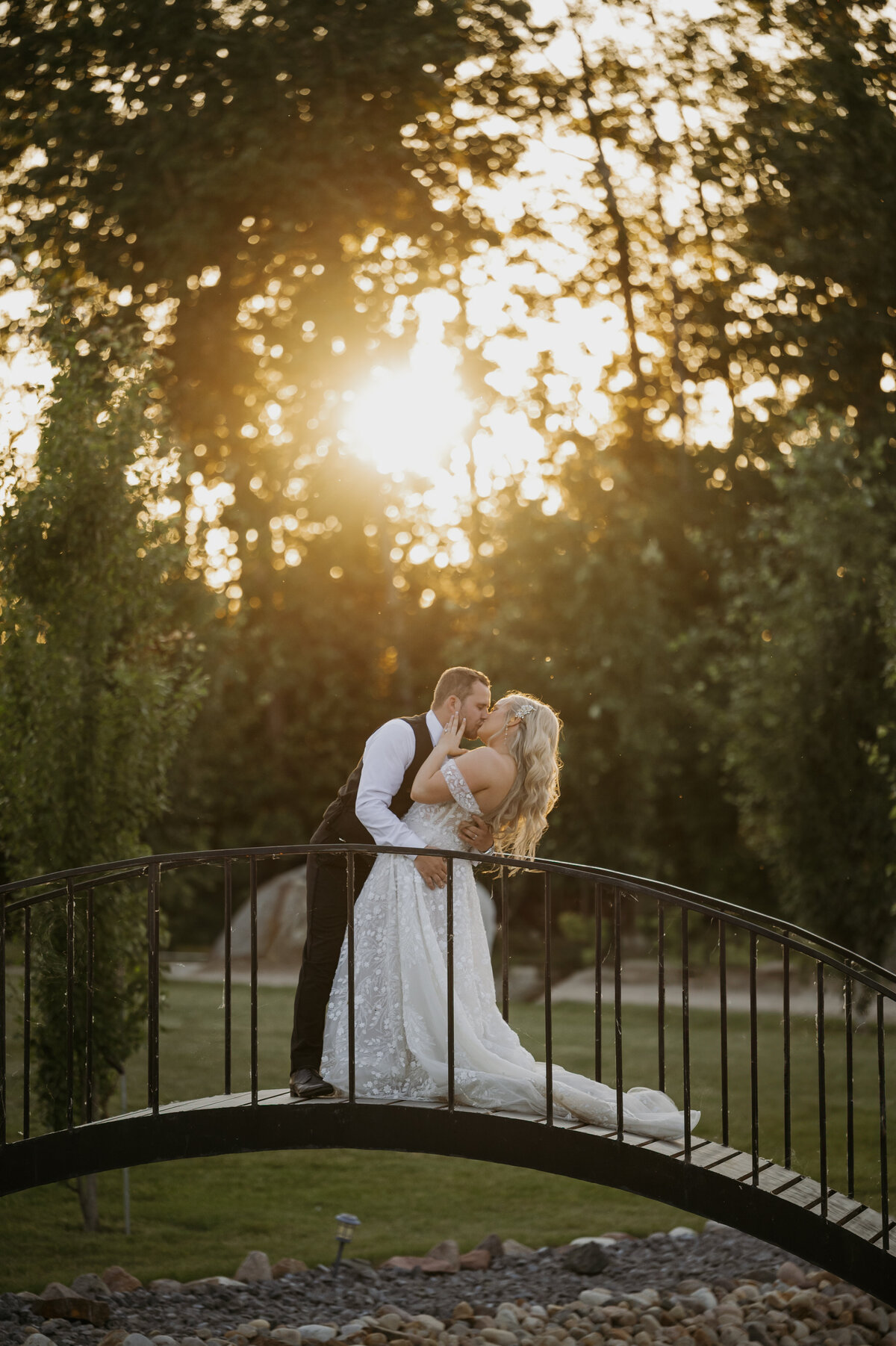 bride and groom kissing on bridgeduring sunset at alberta venue