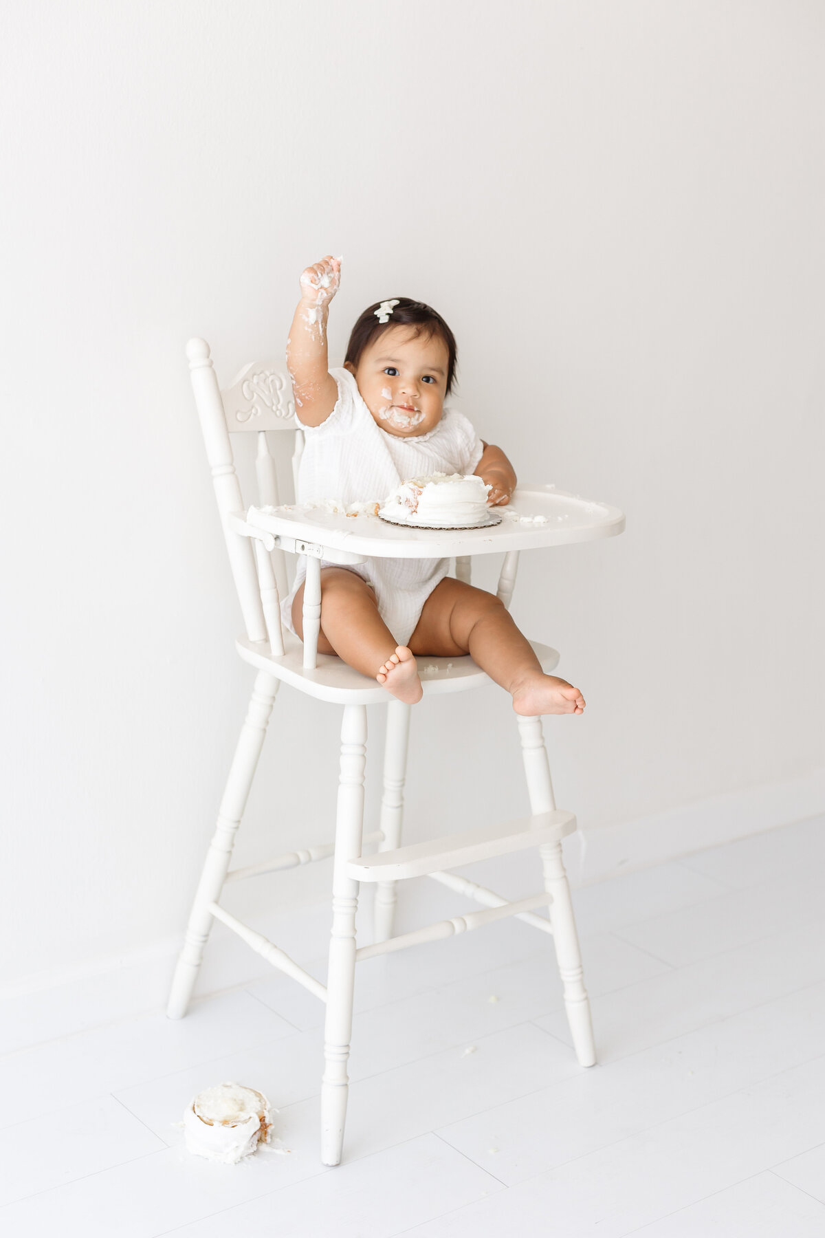 baby smashing cake on high chair