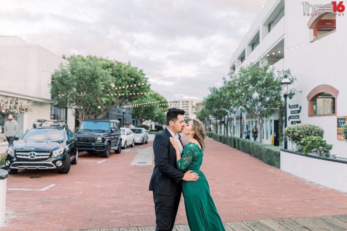 Engaged couple stop in the middle of the street to share a romantic kiss