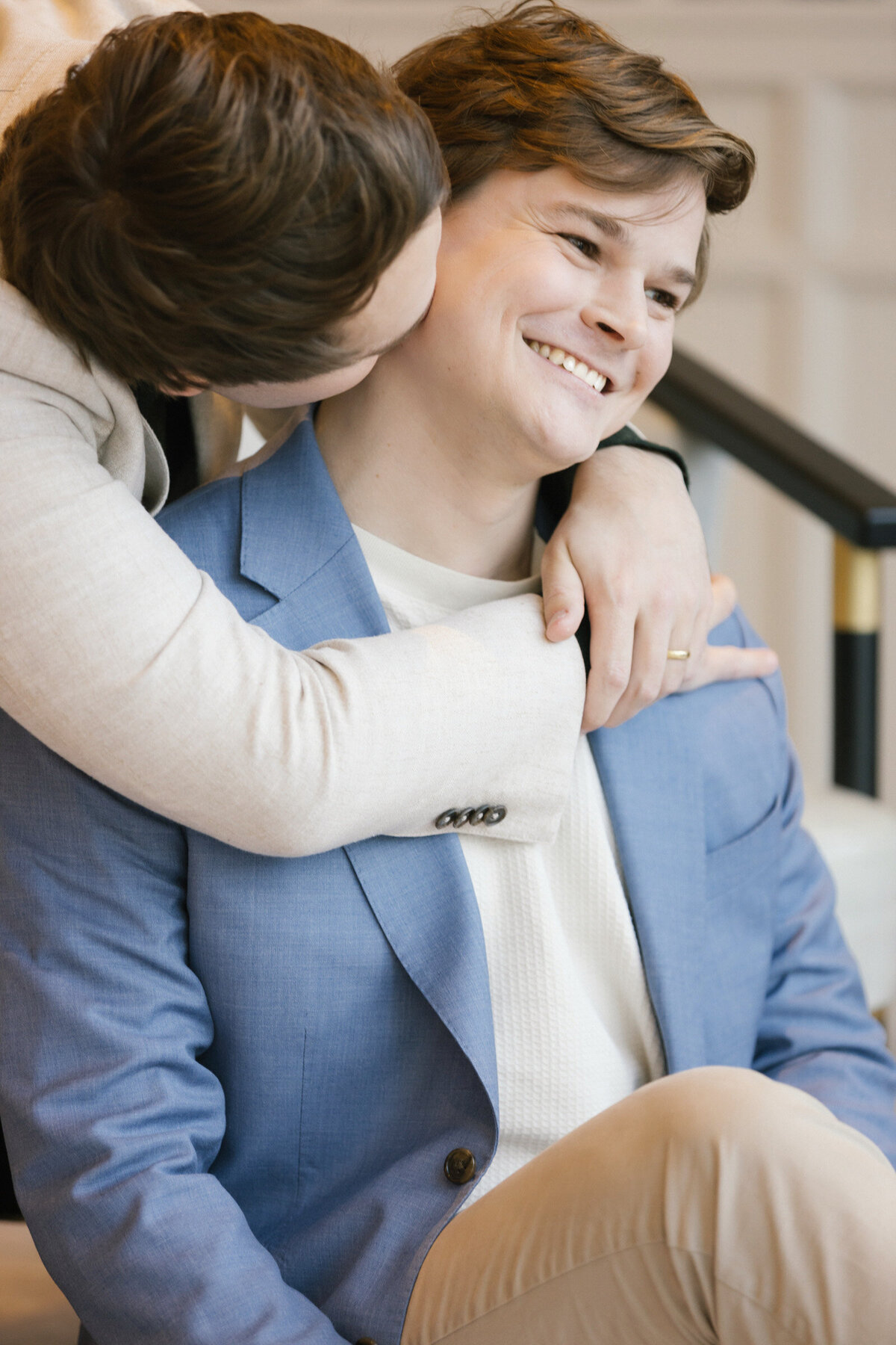 Two grooms snuggling candidly at Hotel Swexen during their same-sex engagement session.