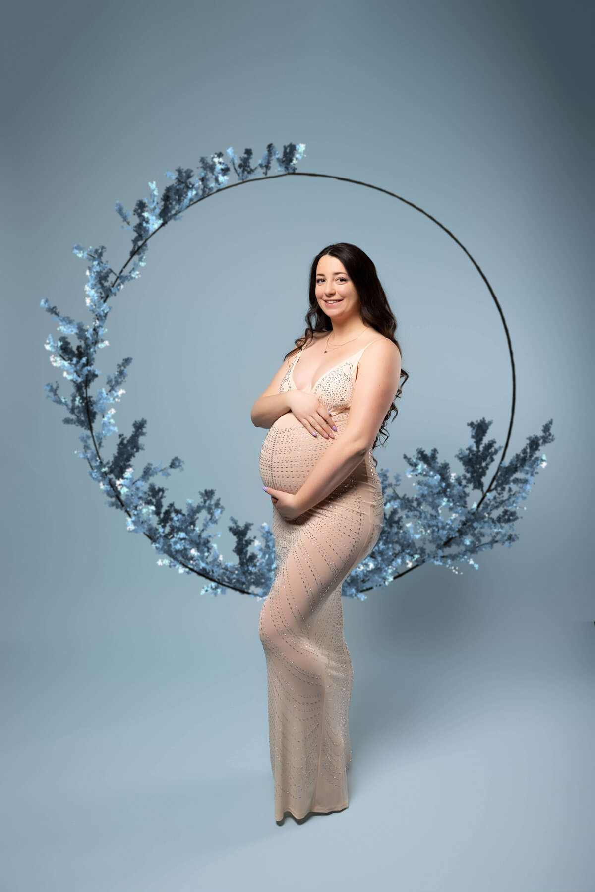 pregnant woman standing in front of floral ring in maternity session with reva davis photography
