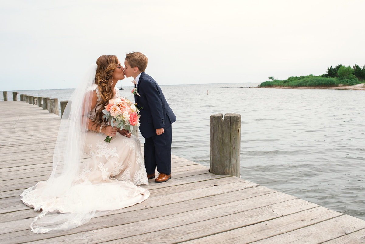 photo of bride kissing the ring bearer on the dock from wedding at Lombardi's on the Bay