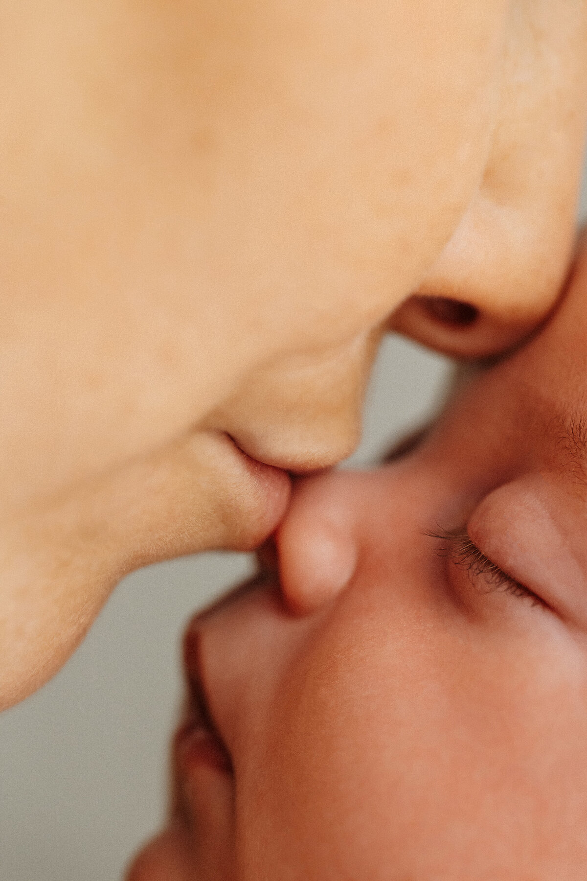 A mother kissing her newborn babies nose during a pose while being photographed in christchurch photographer lucy janes studio