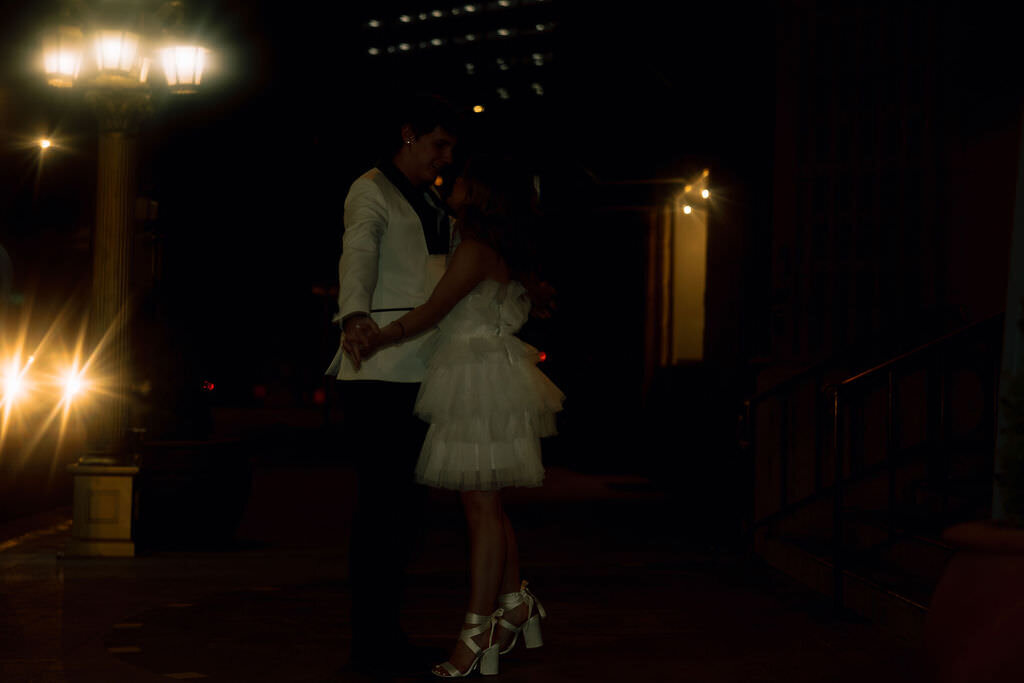 A wedding couple holding hands and kissing.