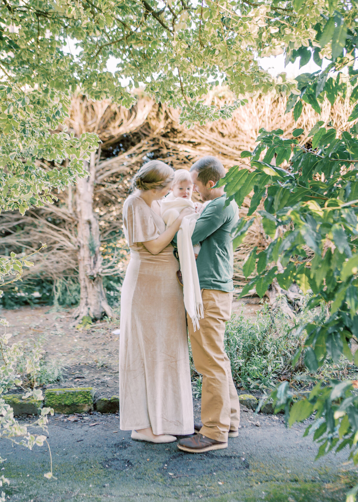Intimate moment of parents snuggling their daughter in gardens by Oklahoma City Family Photographer Courtney Cronin