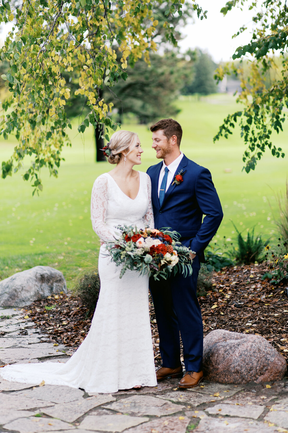 Bride and Groom standing next to each other and looking at each other with smiles. Captured by Minnesota wedding photographer. 
