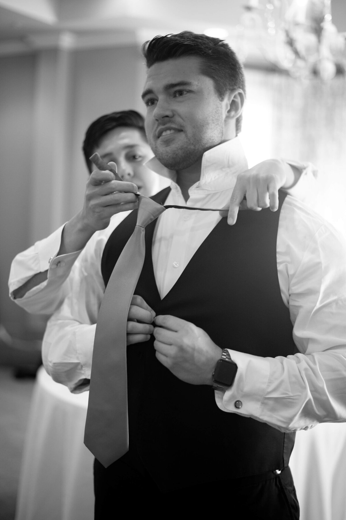 Woman helping groom put on tie