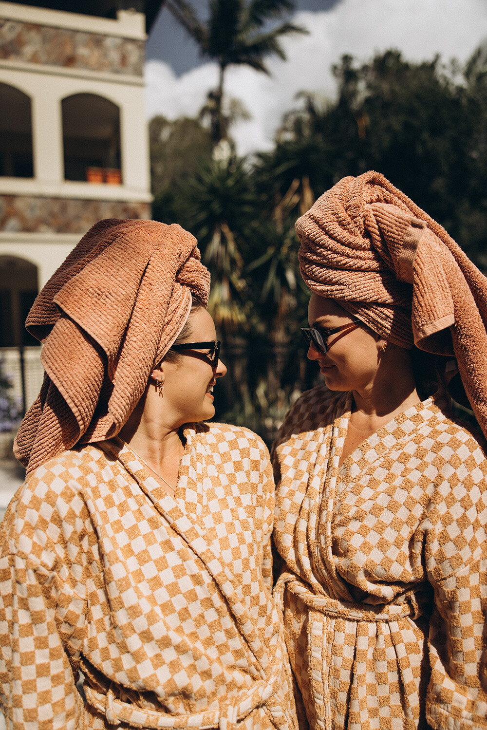 Playful brand moment between two women in matching robes, captured by Sunshine Coast branding photographer to show connection and joy.