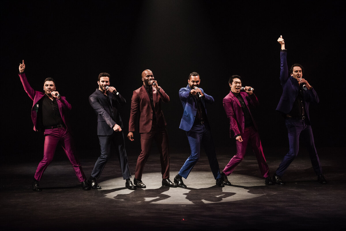A group of people in suits singing on stage