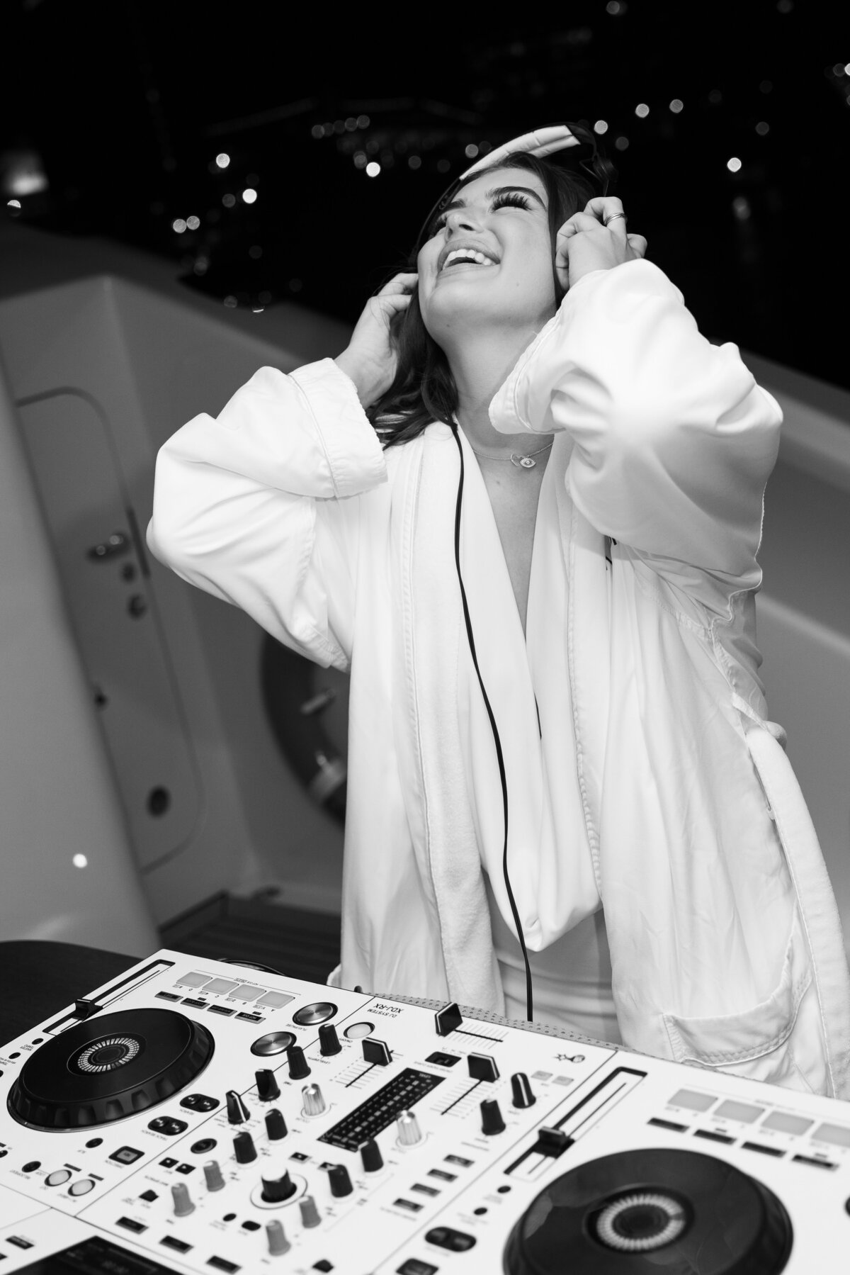 vibrant and candid shot of a DJ enjoying the music, headphones on and eyes closed in bliss. This black-and-white photograph beautifully captures the energy and passion of the moment during the yacht party.
