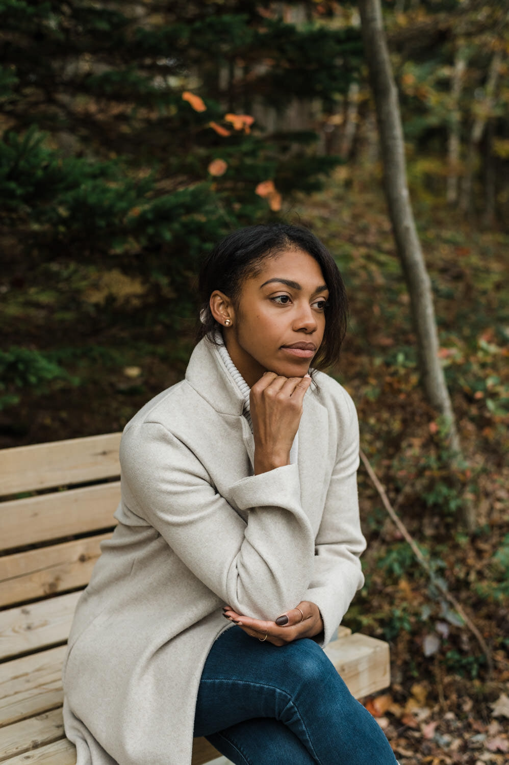 Woman sitting on a bench during fall portrait photography session.